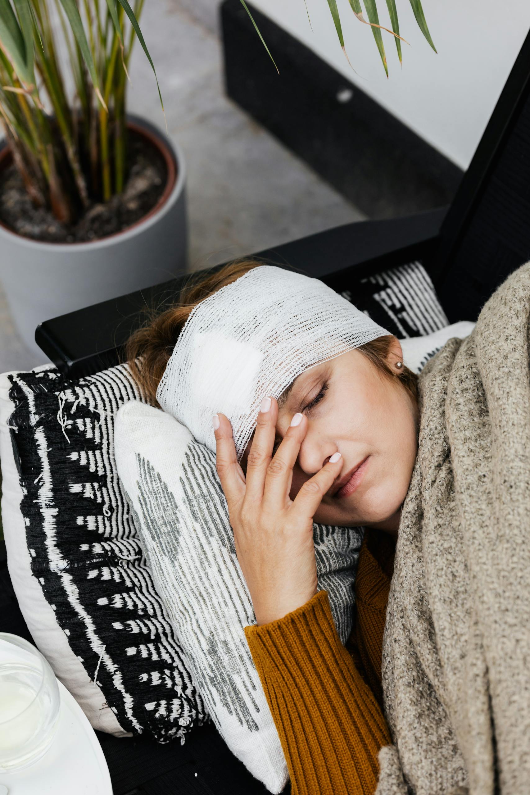 A woman with a head injury rests indoors, showcasing the warmth of a cozy, home environment.